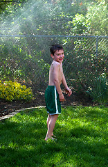 Image showing boy sprayed by sprinkler