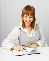 Image showing Attractive girl in a white blouse with a notepad and pen