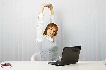 Image showing tired girl with a laptop stretches