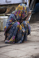 Image showing Terrified woman hiding under cover from punishment.