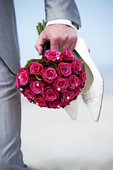 Image showing Groom holding flowers en shoes of bride