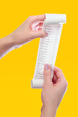 Image showing woman holds in her hands roll of paper with printed receipt 