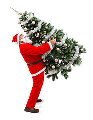 Image showing Santa Claus carrying a decorated christmas tree