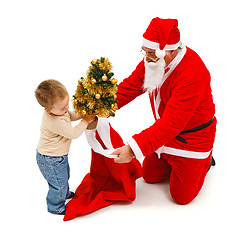 Image showing Little boy puts small tree in Santa's bag