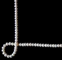 Image showing White pearls on the black silk as background