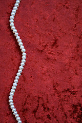 Image showing Necklace of white pearls on a terracotta velvet as background 