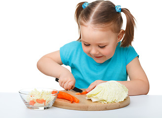 Image showing Little girl is cutting carrot for salad