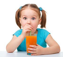 Image showing Little girl drinks orange juice