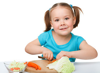 Image showing Little girl is cutting carrot for salad