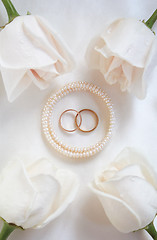 Image showing Wedding rings and roses as background 