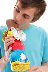 Image showing Boy biting ear of chocolate rabbit