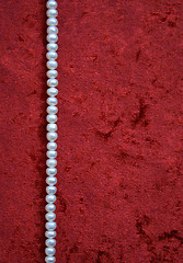 Image showing Necklace of white pearls on a terracotta velvet as background 