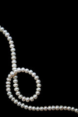 Image showing White pearls on the black silk as background 