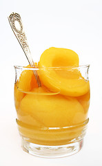 Image showing Peaches in a sweet syrup in a glass isolated on the white