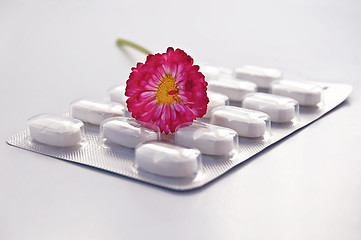 Image showing White round pill with daisy