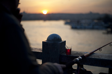 Image showing Man fishing from bridge in sunset