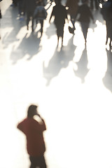 Image showing Crowd in sunlight with person on phone