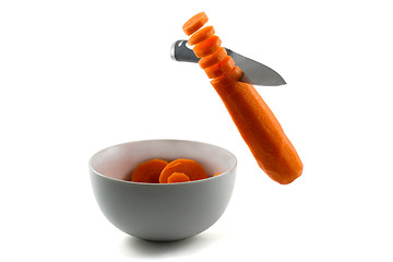 Image showing Knife chopping carrot slices into white bowl