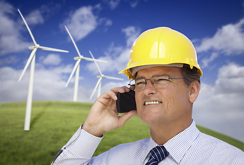 Image showing Hard Hat Wearing Engineer on Phone with Turbines Behind