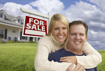 Image showing Happy Couple Hugging in Front of Real Estate Sign and House