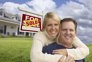 Image showing Happy Couple Hugging in Front of Sold Sign and House