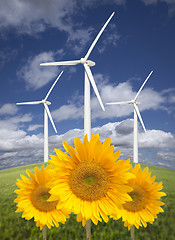 Image showing Wind Turbines Against Dramatic Sky with Bright Sunflowers