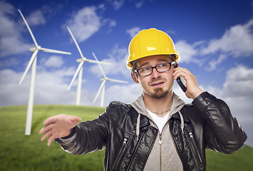 Image showing Hard Hat Wearing Engineer on Phone with Turbines Behind