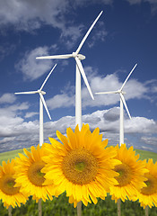 Image showing Wind Turbines Against Dramatic Sky with Bright Sunflowers