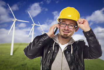 Image showing Hard Hat Wearing Engineer on Phone with Turbines Behind