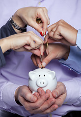 Image showing Hands inserting money in the piggybank