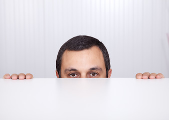 Image showing Businessman peeking behind the desk