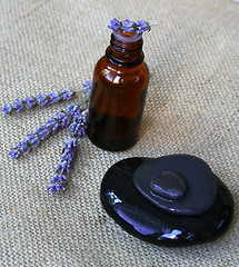 Image showing Lavender flowers and bottle of essential oil on sackcloth backgr
