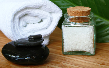 Image showing White bath towel, bottle of sea salt and stones in spa compositi