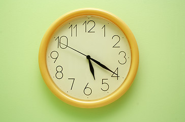 Image showing Yellow wall clock on the green