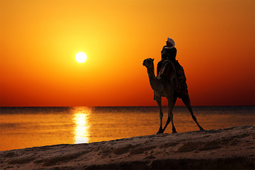 Image showing bedouin on camel silhouette against sunrise