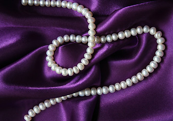 Image showing White pearls on a lilac silk as background 