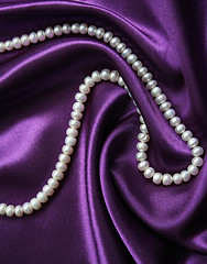 Image showing White pearls on a lilac silk as background 