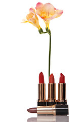 Image showing glamor red shiny lipstick and yellow flower