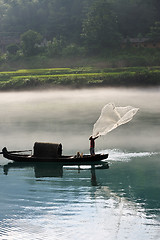 Image showing Fisherman casting net on river