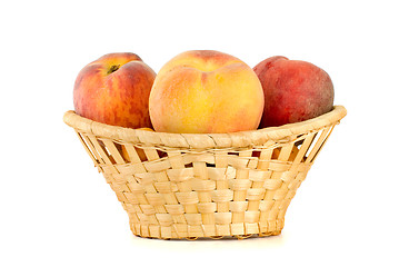 Image showing Three tasty peaches in wicker basket