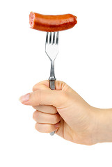 Image showing Hand holding half eaten sausage on fork.