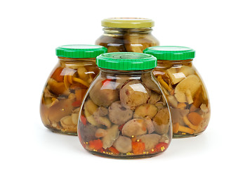 Image showing Four glass jars with marinated mushrooms