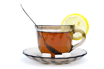 Image showing Teacup with black tea, teaspoon, dish, lemon slice and some sugar pieces