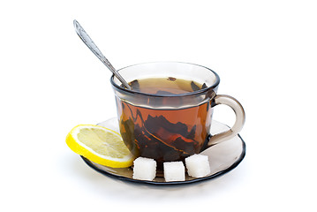 Image showing Teacup with black tea, teaspoon, dish, lemon slice and some sugar pieces