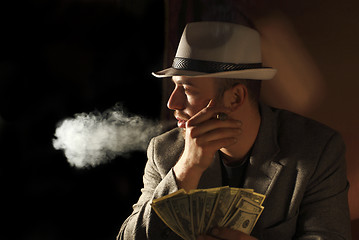 Image showing amn smoke and hold few dollars in his hand