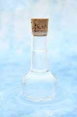 Image showing Bottle of clean  water  in water ripples over colored background