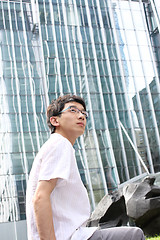 Image showing businessman sitting on a bench in front of an office building 