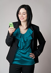 Image showing Smiling woman looking at her cell phone