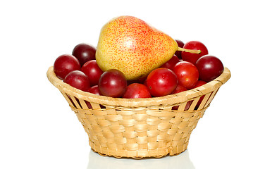 Image showing Wicker basket with cherry plums and yellow-red pear