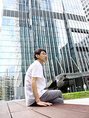 Image showing businessman sitting on a bench in front of an office building 